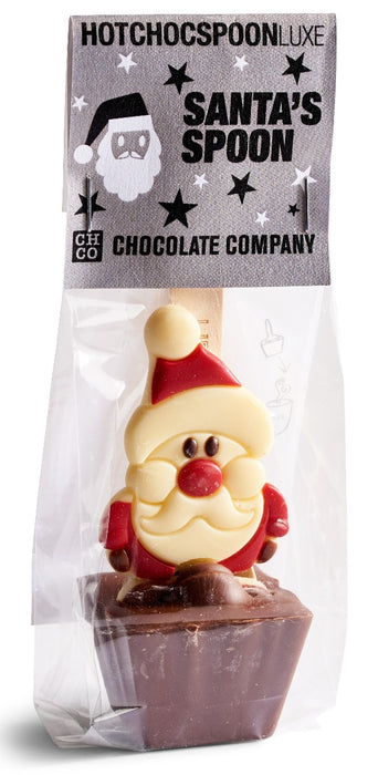 A packaged Santa's Spoon chocolate from Hotchoc Spoon Luxe by CH CO Chocolate Company. The product is a chocolate spoon shaped like Santa Claus, featuring a cream-colored face and beard, a red hat and coat, and a red nose, set in a dark chocolate base and sealed in a clear plastic bag with a branded paper header.