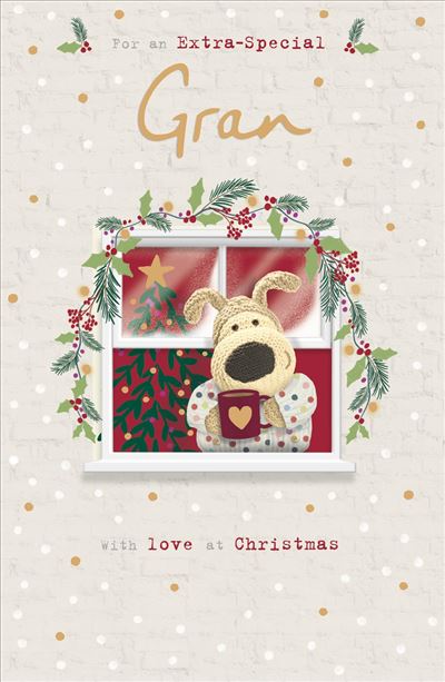 A Christmas greeting card design with the text 'For an Extra-Special Gran with love at Christmas.' The center shows a knitted dog character sitting in front of a window decorated with holly, pine branches, red berries, and a small Christmas tree.