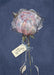 Watercolor-style artwork of a single pale pink peony flower in a clear glass vase against a dark blue background, with a small hanging tag that reads 'with sympathy'.