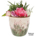 An artificial floral arrangement in a distressed ceramic pot with pink flowers and green foliage, on a white background with a text overlay that says 'Plants not included'.
