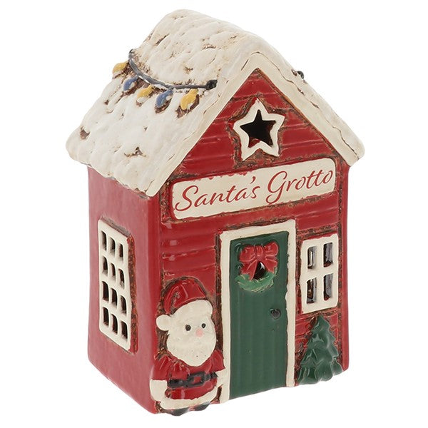 A Christmas-themed ceramic ornament shaped like a red cabin labeled 'Santa's Grotto,' with a white snow-covered roof, green door, Santa figure, and small tree on a white background.