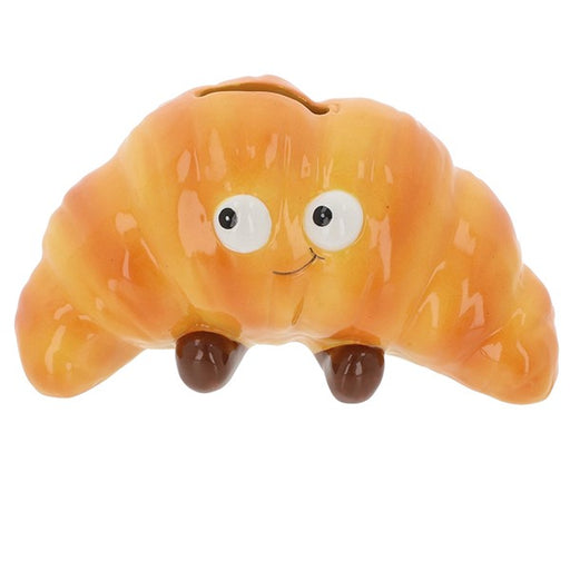 Toy croissant with googly eyes and a smile on a white background