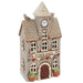 A small decorative ceramic model of a town hall building with a clock face on the tower, arched windows, a brown door, potted plants at the base, and a white background.