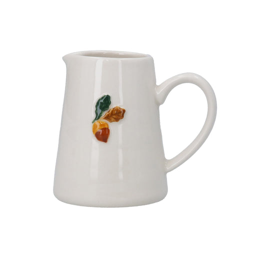 A white ceramic pitcher with a small hand-painted fruit design featuring green, brown, and orange details on the front, set against a plain white background.