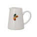 A white ceramic pitcher with a small hand-painted fruit design featuring green, brown, and orange details on the front, set against a plain white background.