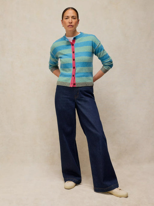 Person wearing a striped sweater and dark pants on a beige background