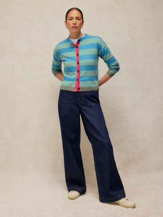Person wearing a striped sweater and dark pants on a beige background