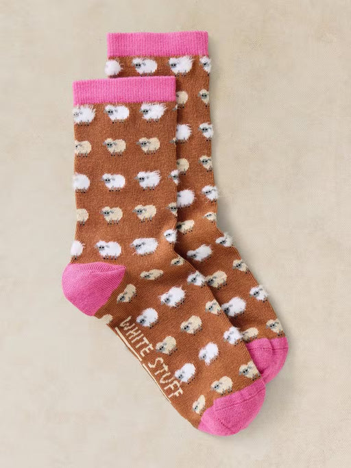 Pair of socks with sheep pattern and pink accents on a beige background