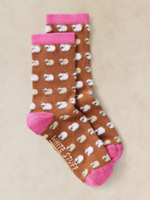 Pair of socks with sheep pattern and pink accents on a beige background
