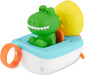 A colorful children's bath toy featuring a green alligator sitting in a white and light blue boat with orange handles and a yellow shell on a white background.