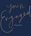 A square navy blue card or sign with elegant script text reading 'you're Engaged' in a gold beaded or dotted outline style, with 'Wonderful News' in smaller white text below.