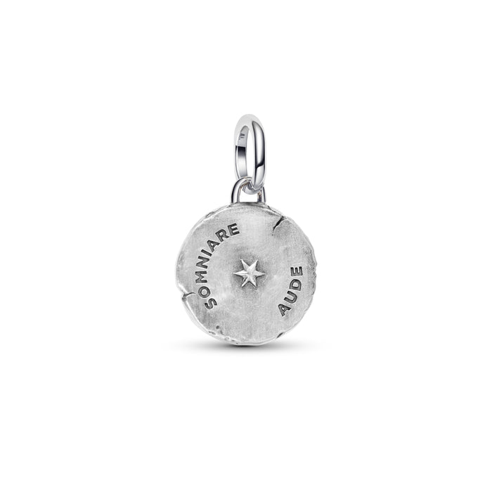 A silver round charm pendant with a textured finish, featuring the engraved words 'SOMNIARE' and 'AUDE' surrounding a central star, shown on a plain white background.
