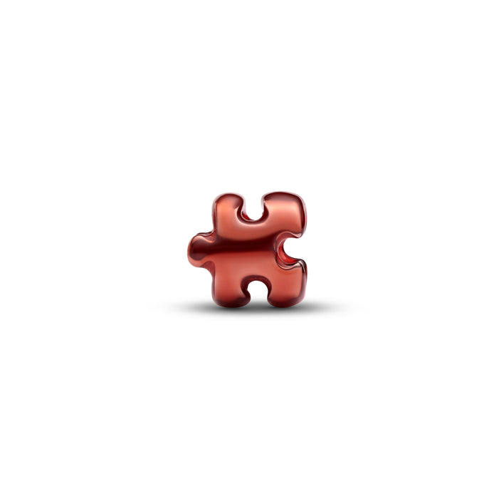 A glossy red puzzle piece charm or pendant centered on a plain white background with a soft shadow underneath.