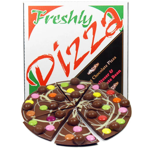 A novelty chocolate and bean pizza toy set with a sliced chocolate pizza in front of its colorful retail box. The toy pizza is made of dark brown chocolate with white drizzle and colorful candy-coated beans, set against a plain white background.