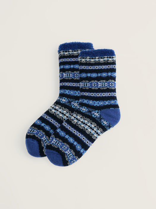 A pair of crew socks with a blue and navy Nordic pattern, featuring light blue and white accents, displayed on a light beige background.