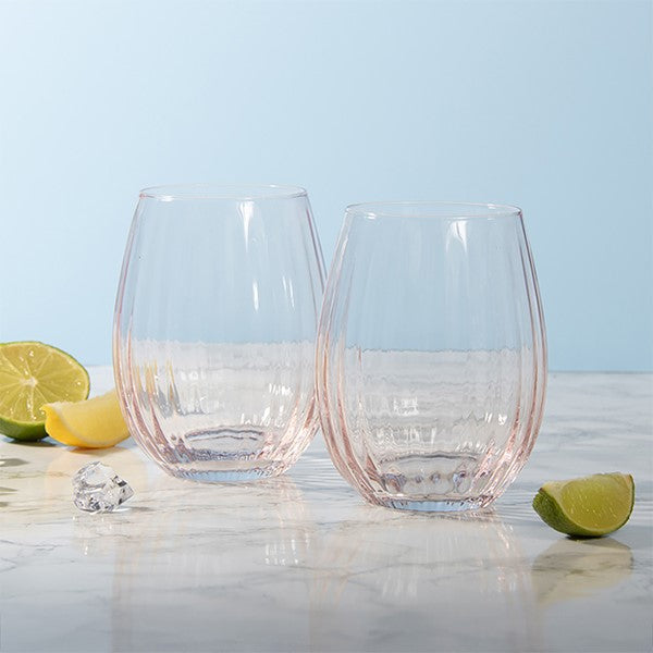 Two clear stemless wine glasses with a textured, ribbed pattern, displayed on a light marble surface with lime wedges and ice cubes against a soft light blue background.