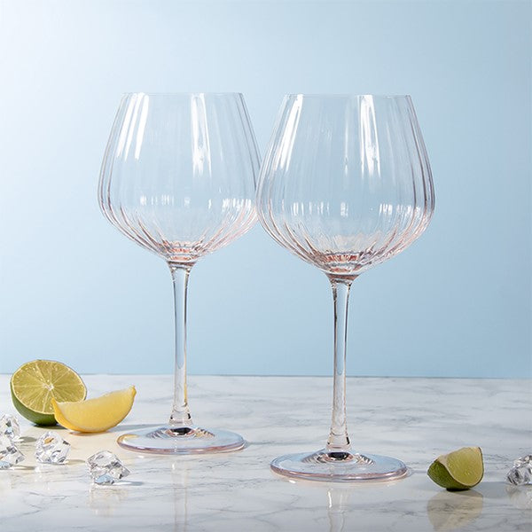 Two clear wine glasses on a marble surface with a light blue background