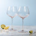 Two clear wine glasses on a marble surface with a light blue background