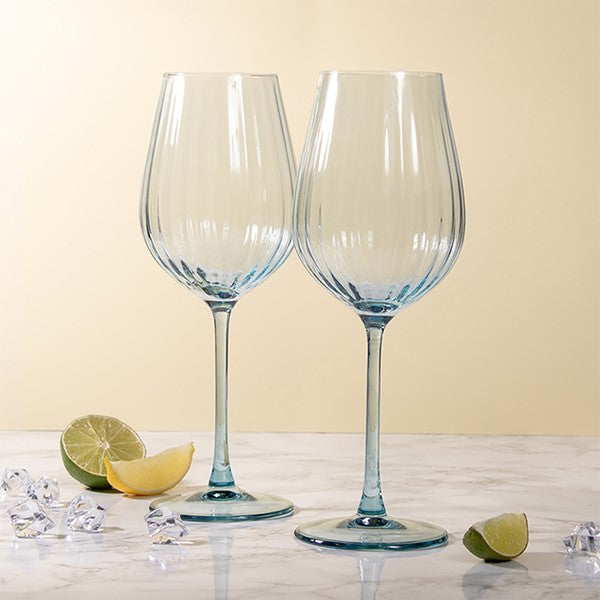 Two blue wine glasses on a light surface with lime wedges and decorative items.