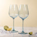 Two blue wine glasses on a light surface with lime wedges and decorative items.