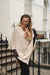 Woman wearing a beige poncho and brown gloves standing on a staircase.