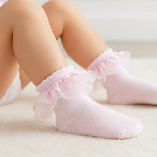 Pink baby socks with ruffles on a light background