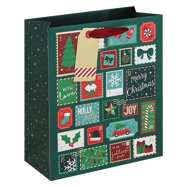 A dark green Christmas advent gift bag with a festive collage of holiday illustrations on the front panel, including stockings, snowflakes, candy canes, and 'Merry Christmas' cards. It has a red handle and a blank beige hang tag attached.