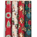 Four rolls of Christmas-themed wrapping paper standing upright side by side. The designs include red with green wreaths and gold script, cream with Santa illustrations and postage stamps, red with Santa portraits and gold accents, and dark green with teal ornaments and gold details.