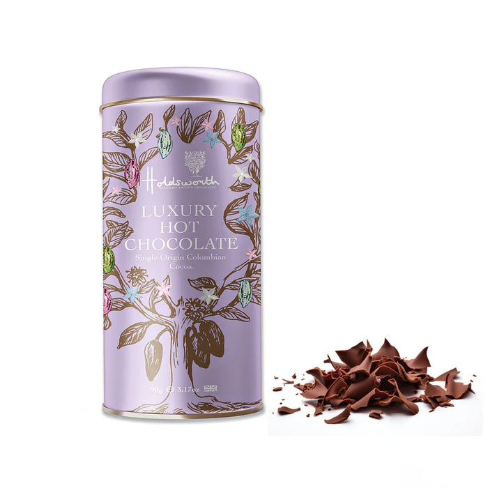 A lavender cylindrical tin of Haldsworth Luxury Hot Chocolate with botanical illustrations, shown next to a small pile of chocolate shavings on a white background.