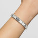 Silver bracelet on a person's wrist against a light gray background