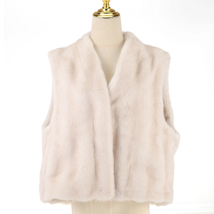 A light beige faux fur vest displayed on a cream-colored mannequin torso with a gold finial, set against a plain white background.