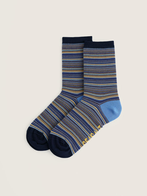 A pair of crew socks with a striped pattern in navy, blue, and yellow, featuring a solid light blue heel and toe, displayed on a light beige background.