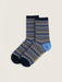 A pair of crew socks with a striped pattern in navy, blue, and yellow, featuring a solid light blue heel and toe, displayed on a light beige background.
