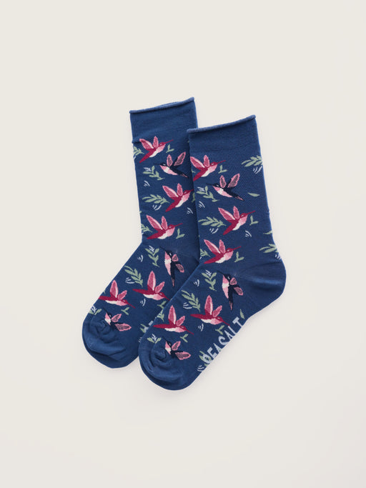 A pair of navy blue crew socks with a repeating pattern of pink and red flowers, green leaves, and small birds, displayed on a light beige background.