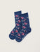 A pair of navy blue crew socks with a repeating pattern of pink and red flowers, green leaves, and small birds, displayed on a light beige background.